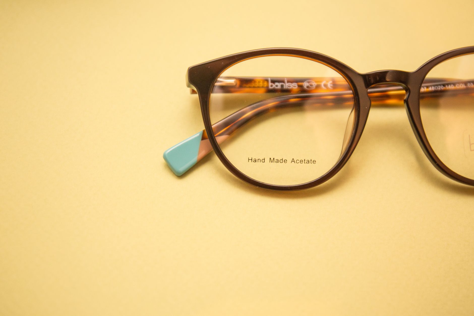 Close-up of handmade acetate brown eyeglasses on a yellow surface, modern design. — illustrating Acetate vs Injection-Moulded Plastic: The Real Difference