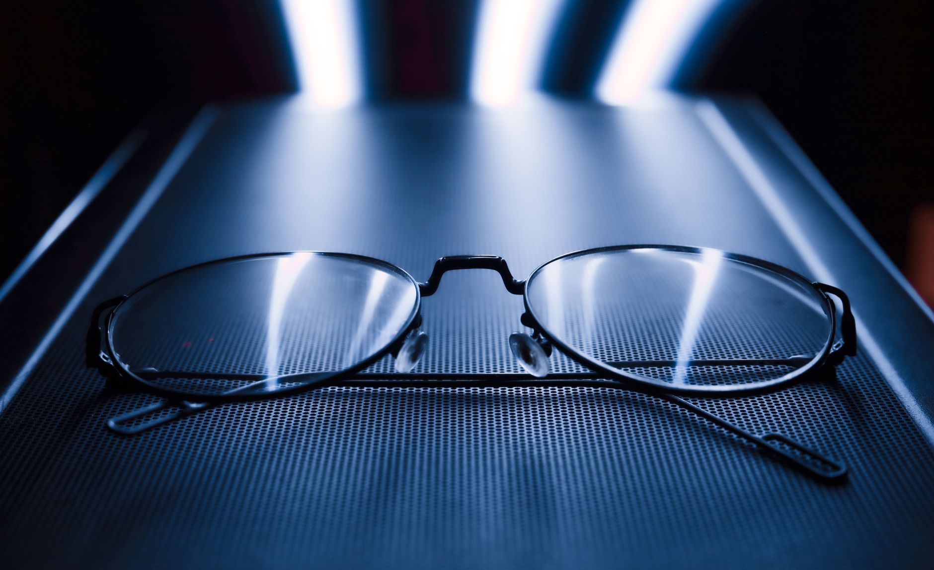 Close-up shot of eyeglasses with a dark blue background and reflective blue light. — illustrating Sunglass Lens Category Numbers 0 to 4 Explained