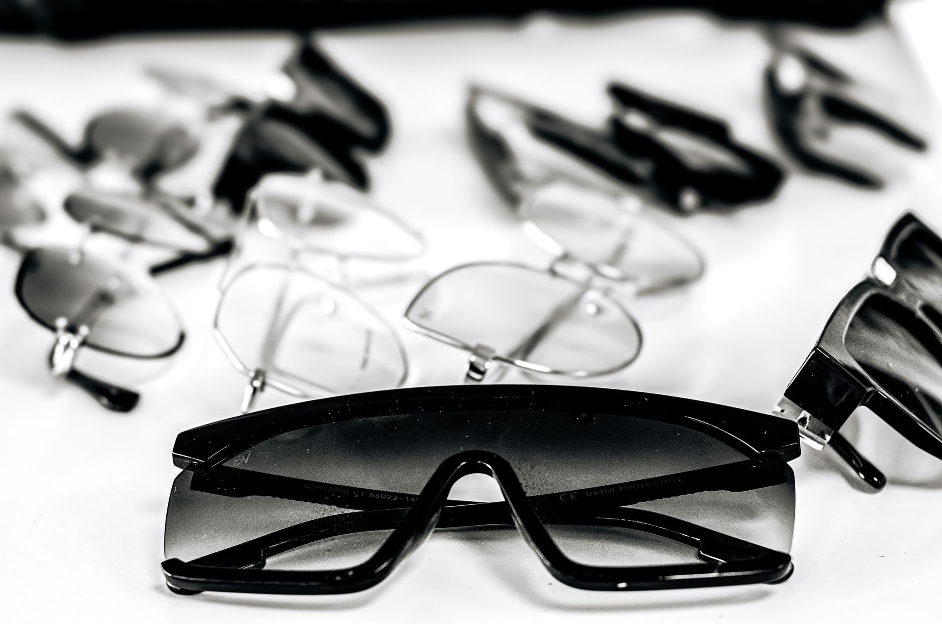 Close-up of various stylish sunglasses and eyeglasses on a white surface, showcasing modern eyewear design. — illustrating UV Protection vs Polarisation: What's the Real Difference