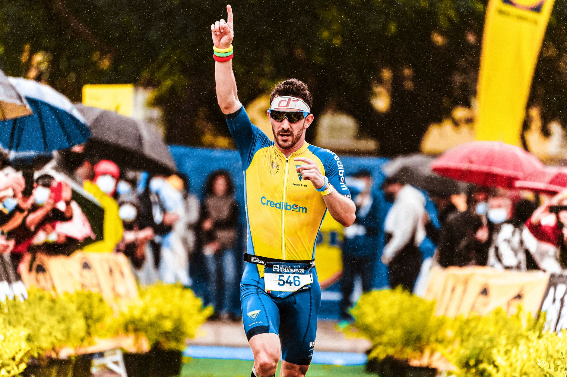 A triumphant marathon runner raising his arm in victory during a rainy sports event. — illustrating What Are Sports Sunglasses Built Differently For?