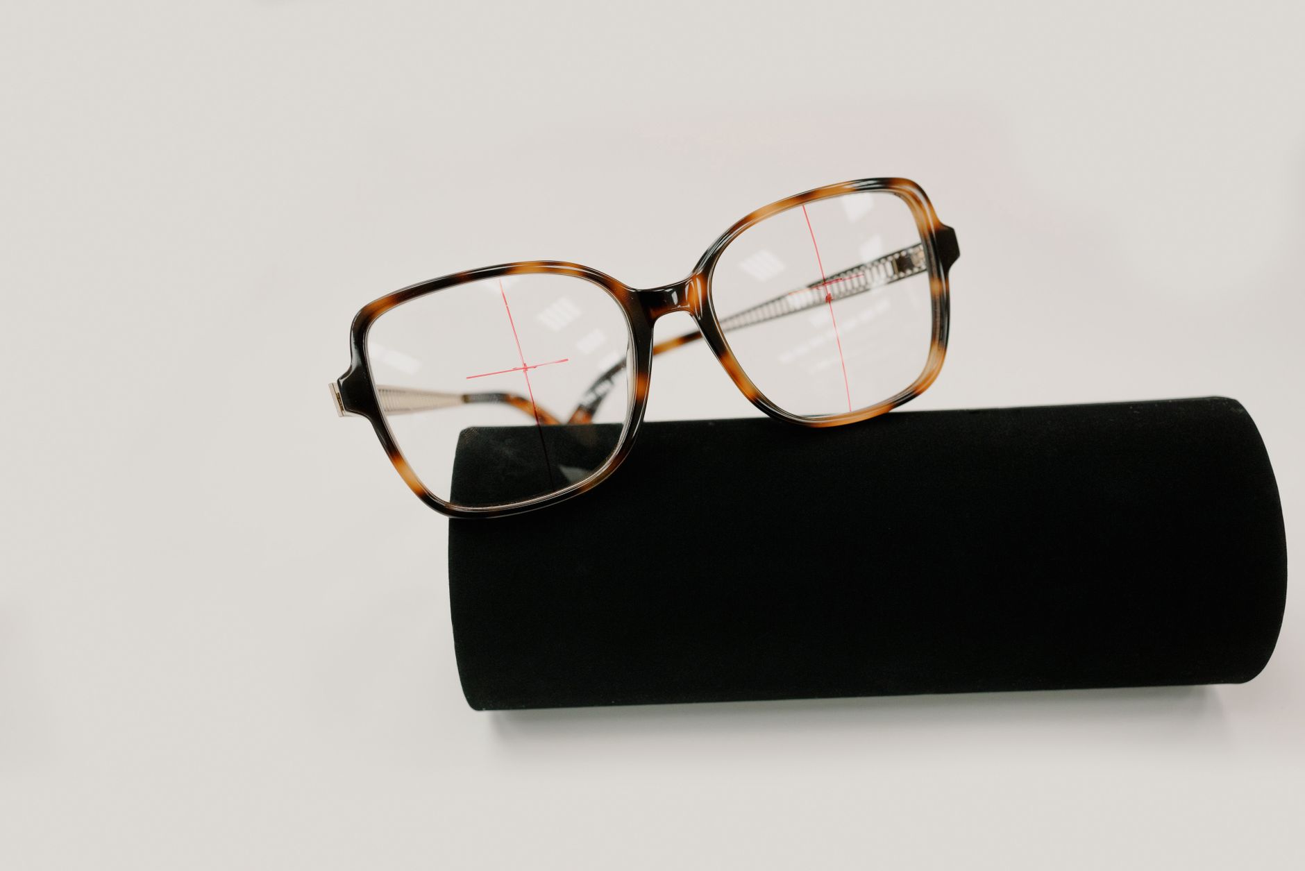 Case under modern spectacles with ornamental plastic frame and flares on lens on white background — illustrating What Is a Progressive Lens? The Adaptation Period Explained