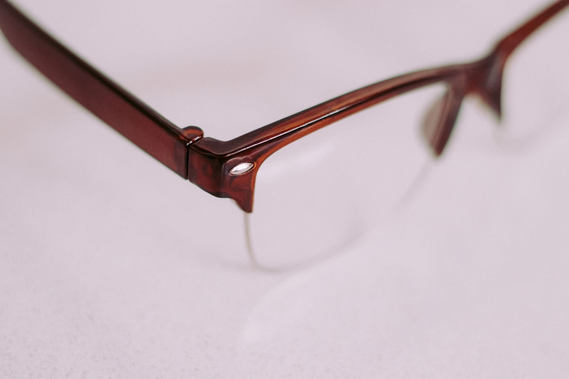 A detailed artistic close-up of a brown vintage style eyeglasses frame with a focus on the corner. — illustrating What Is a Spring Hinge, and How Does It Fail?