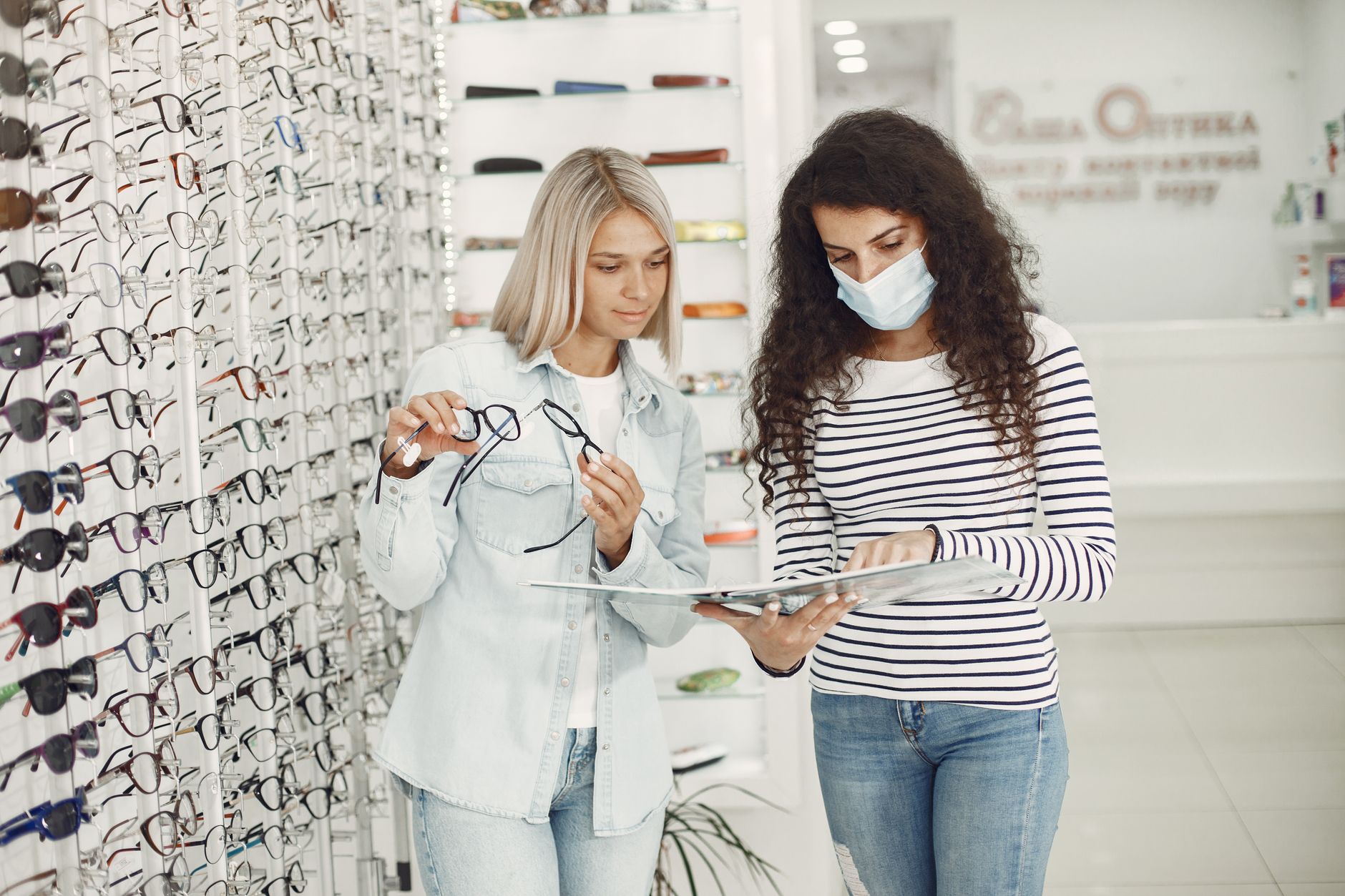 Two women examining glasses options at an optician's shop, deciding on the perfect pair. — illustrating What Questions Are Worth Asking a Dispensing Optician?