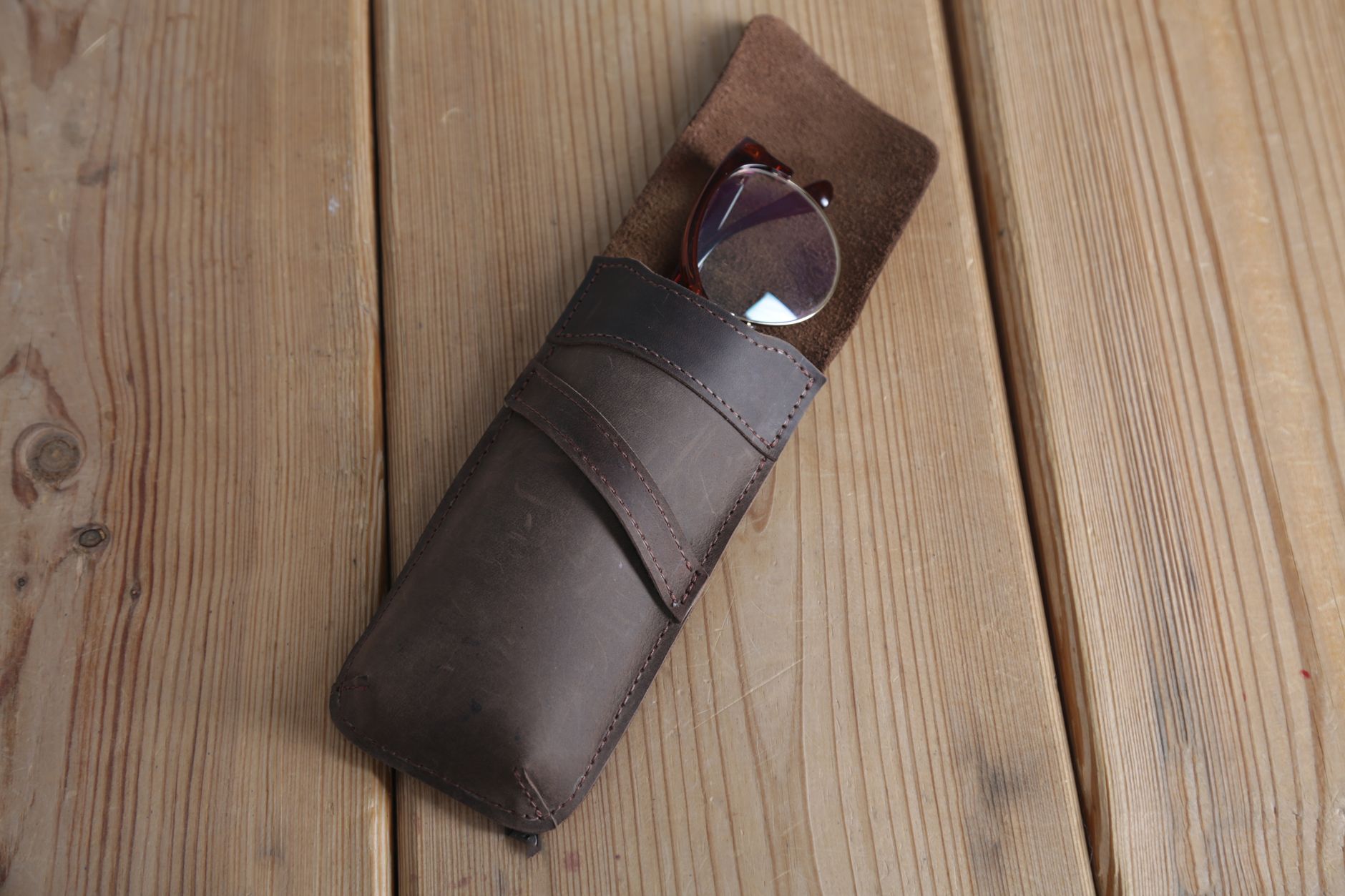 A stylish leather eyeglass case with glasses on a rustic wooden surface. Perfect for accessory showcases. — illustrating When Is a Frame Worth Repairing? A Practical Guide