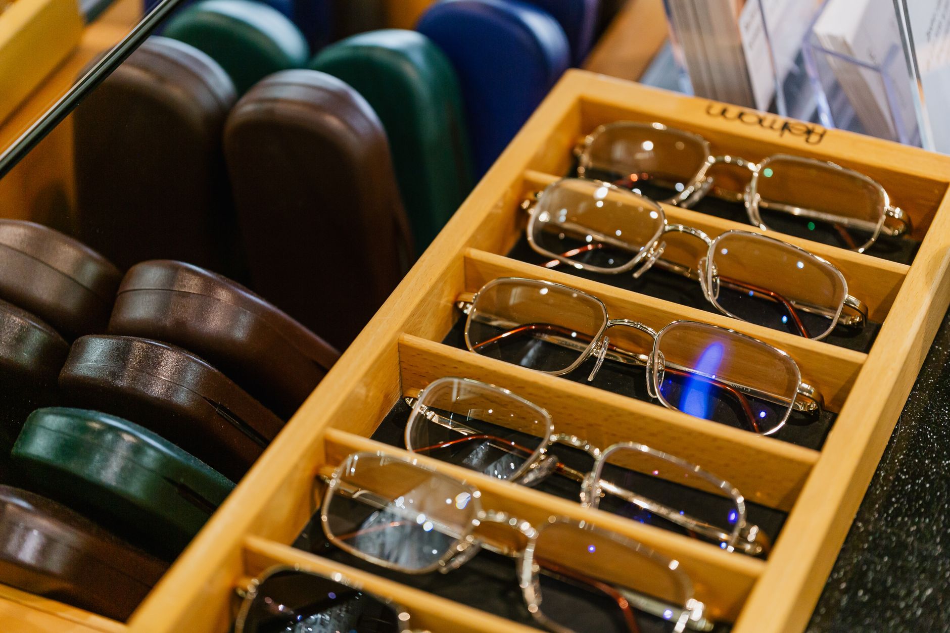 Neatly arranged eyeglasses in a stylish wooden display case at an optician's shop. — illustrating When Is a Frame Worth Repairing? A Practical Guide