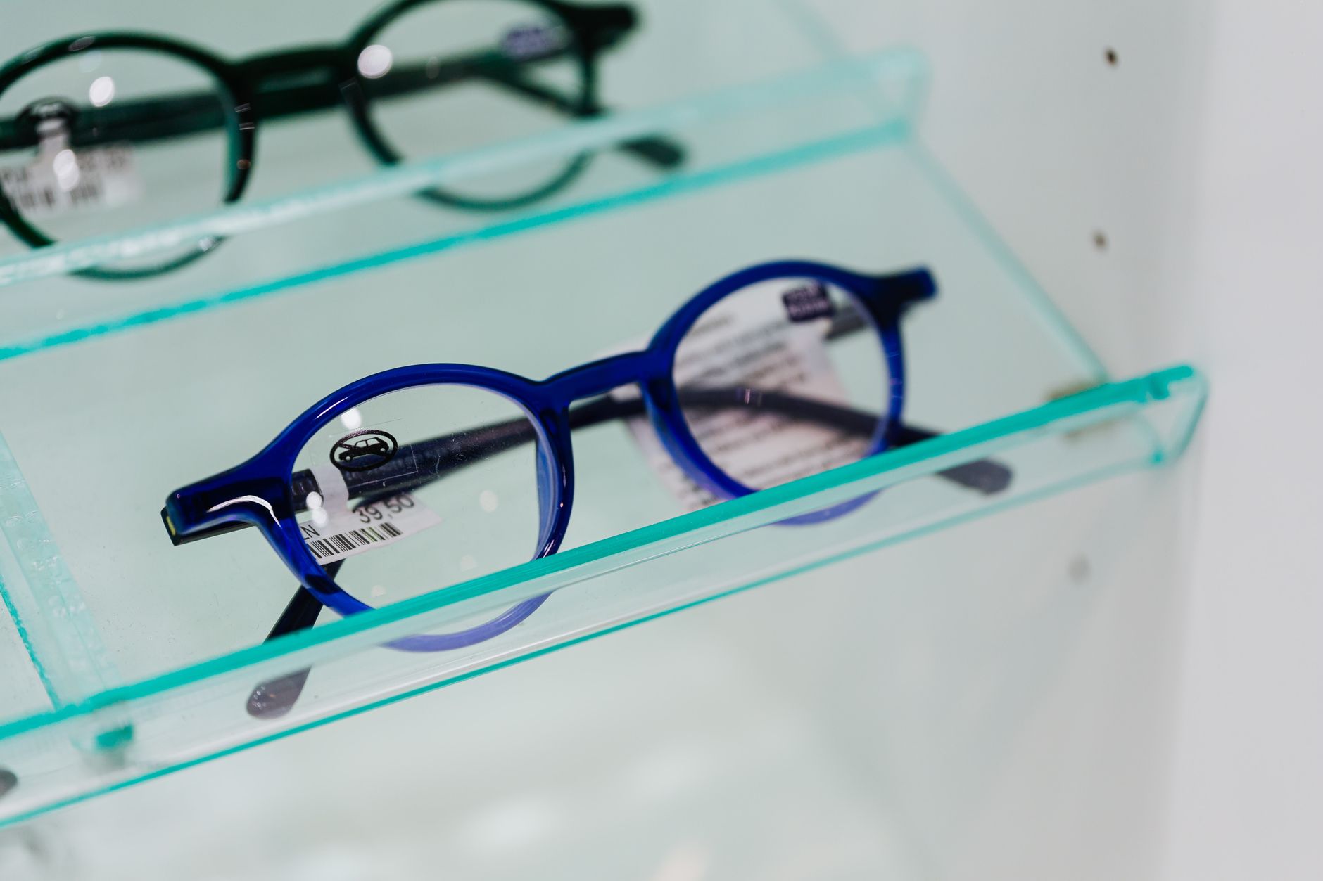 Modern blue eyeglasses showcased in a glass display case, perfect for fashion and optics themes. — illustrating Why Clear and Translucent Frames Look Different on Everyone