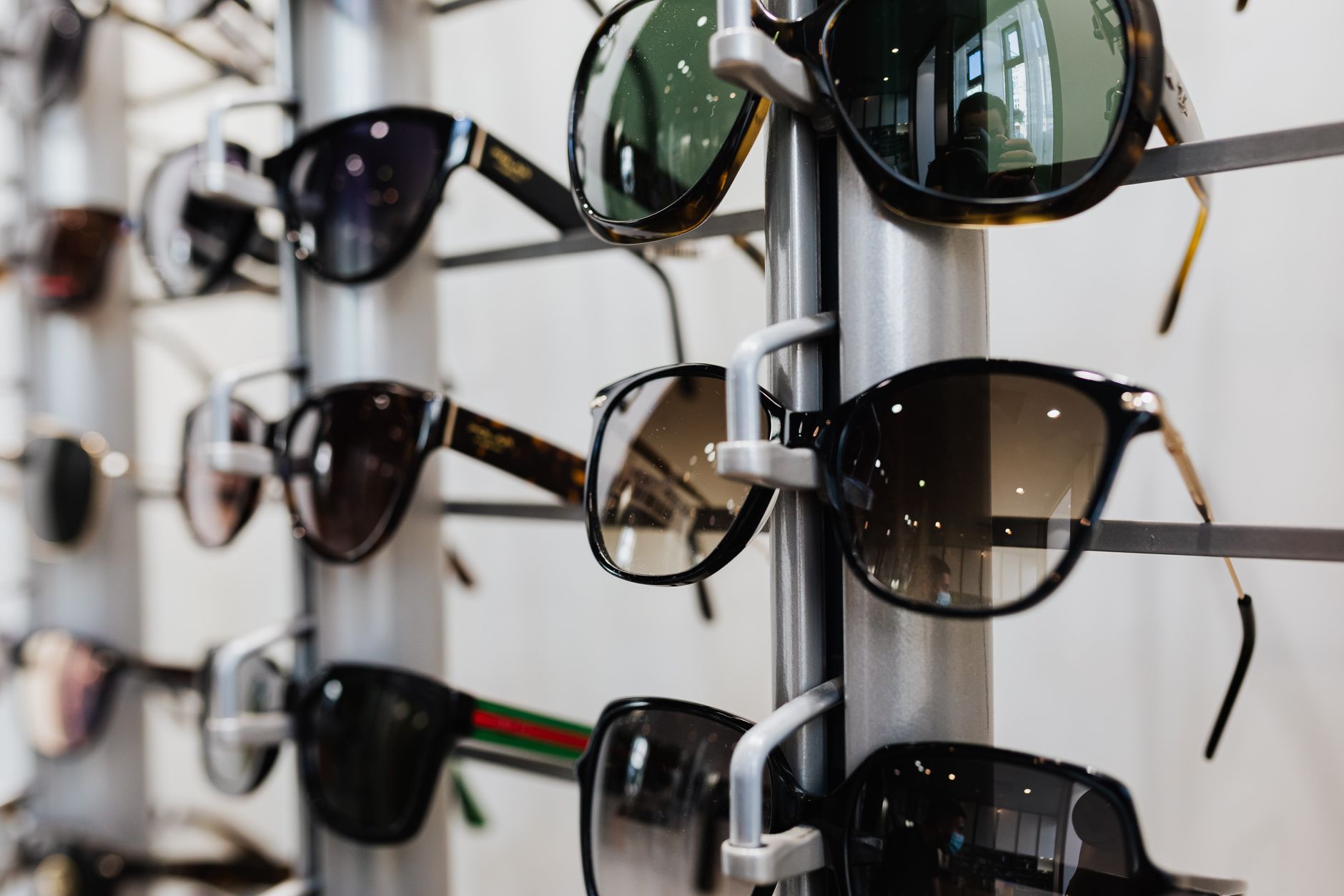 Close-up view of stylish sunglasses displayed on a rack in a retail store. — illustrating Why Dark Lenses Without UV Protection Are Worse Than None
